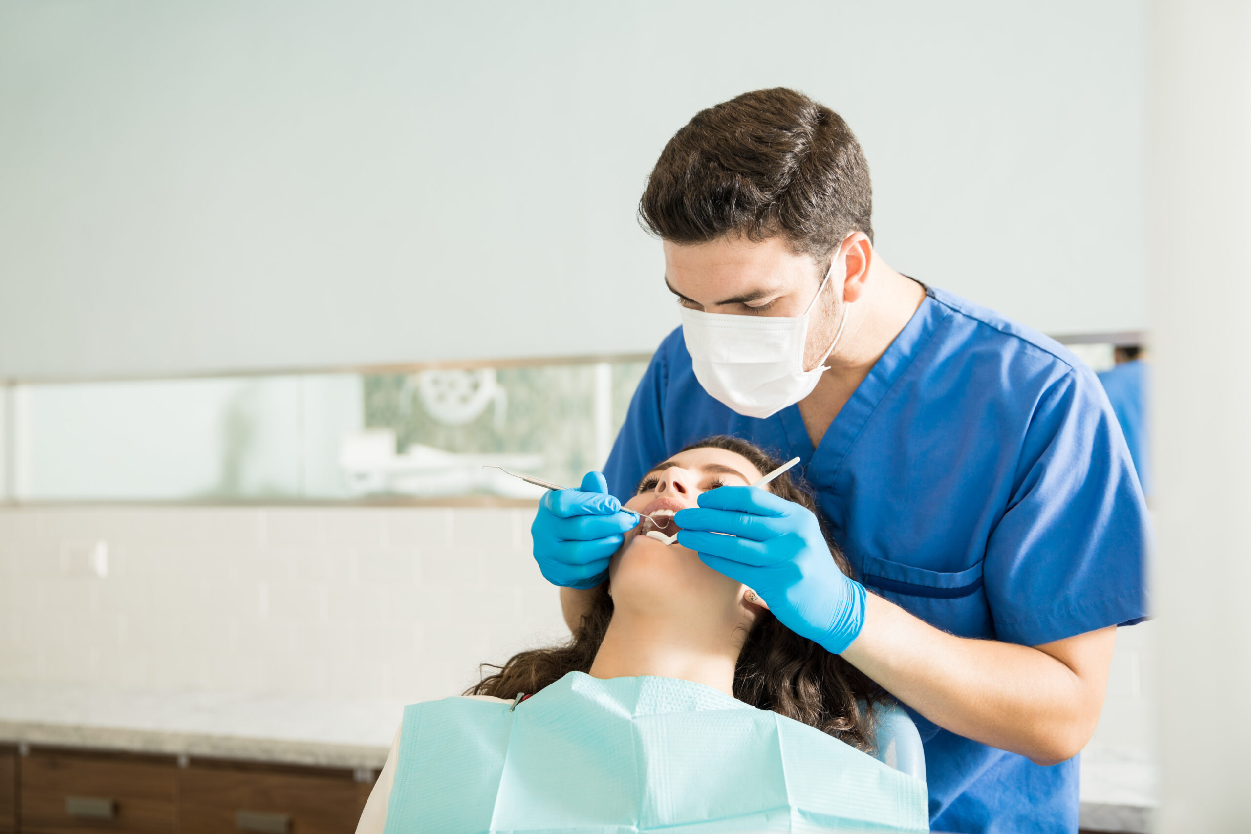 Dentista examinando paciente durante procedimento odontológico em uma clínica.