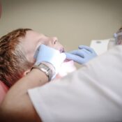 Dentista realizando um exame odontológico em um paciente, destacando a prática clínica segura